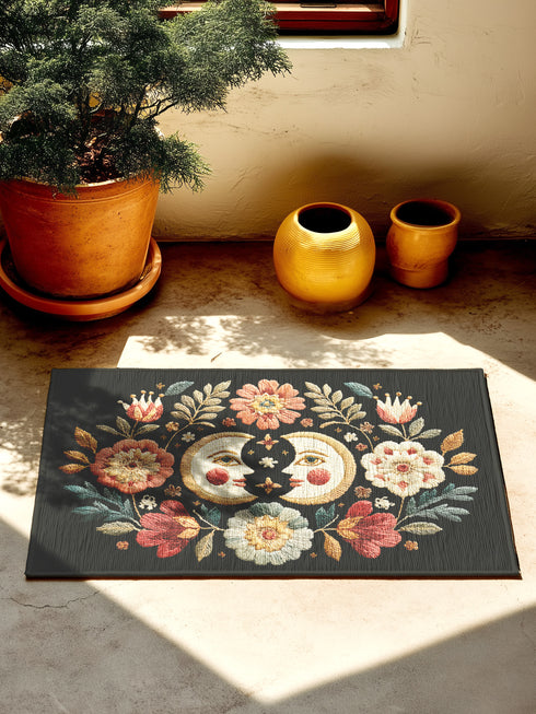 Witchy outdoor doormat featuring a central all-seeing eye, crescent moons, and floral details in an embroidery-style design. This weatherproof welcome mat measures 26x18 inches and is ideal for porches or patio entries. Symbolic celestial motifs offer intuitive protection and spiritual elegance for magical home decor.